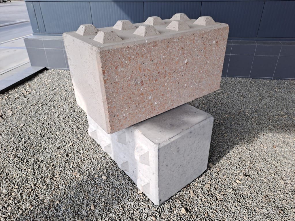 Stacked precast concrete blocks with pyramid locking studs, showing exposed-aggregate finish for earth-sheltered walls