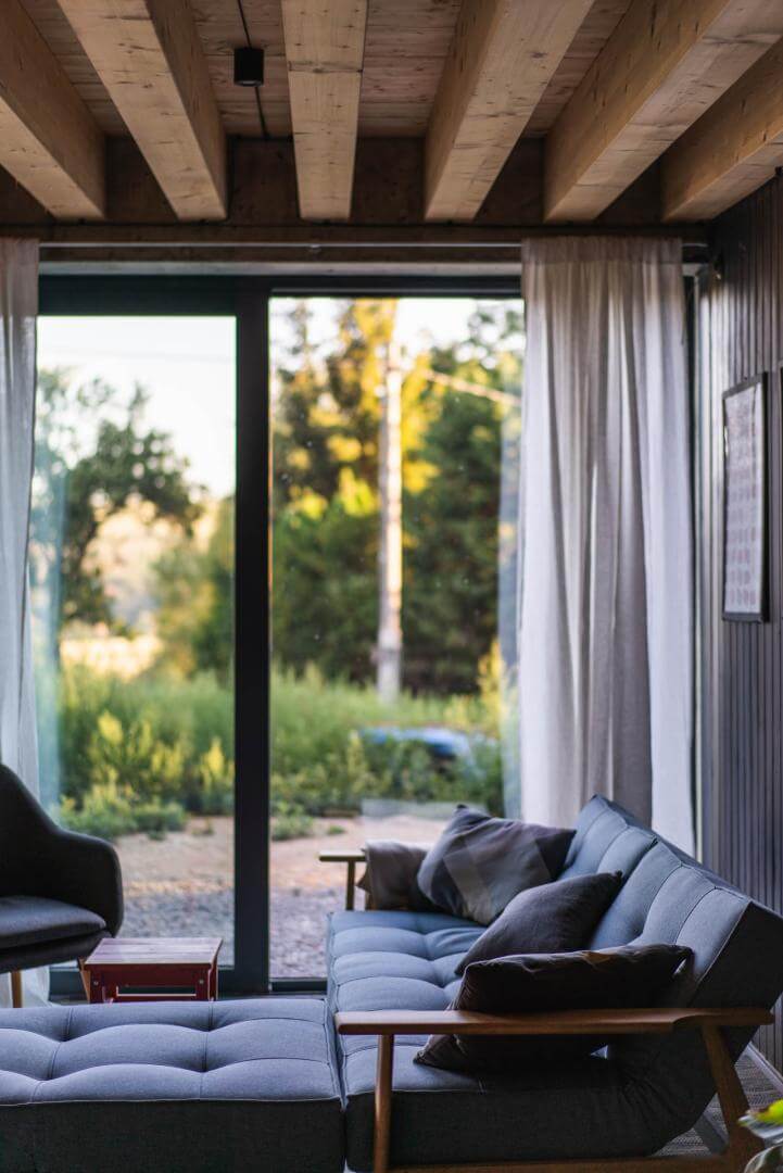 Cozy earth-sheltered living room with tufted sofa facing sliding glass doors and a garden view